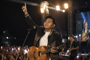penyanyi membawakan musik daerah dengan gitar akustik