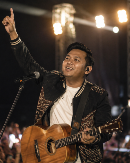 penyanyi membawakan musik daerah dengan gitar akustik