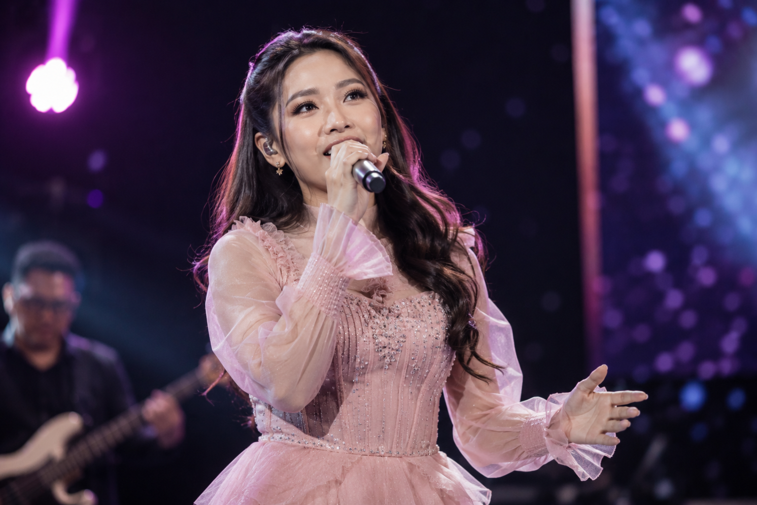 Tiara Andini tampil membawakan lagu di atas panggung konser dengan pencahayaan profesional dan penonton memenuhi area pertunjukan