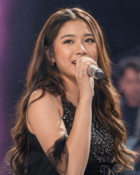 Tiara Andini tampil membawakan lagu di atas panggung konser dengan pencahayaan profesional.