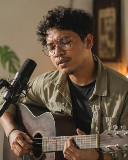 Budi Doremi tampil bernyanyi di atas panggung dengan gitar akustik dan pencahayaan konser yang hangat