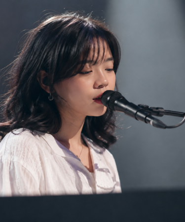 Feby Putri tampil membawakan lagu dengan gitar akustik di atas panggung konser, menggambarkan karakter musik folk-pop yang khas.