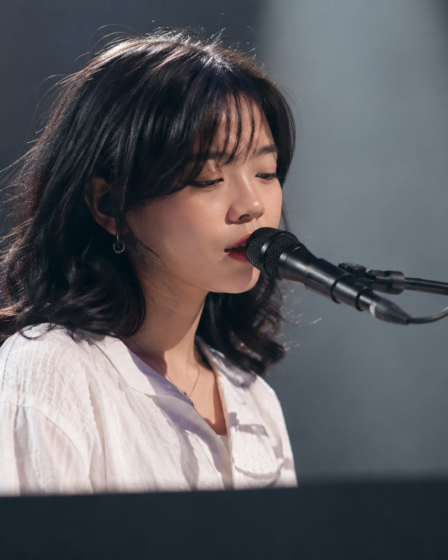 Feby Putri tampil membawakan lagu dengan gitar akustik di atas panggung konser, menggambarkan karakter musik folk-pop yang khas.