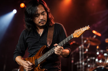 Dewa Budjana memainkan gitar elektrik saat tampil di atas panggung konser musik