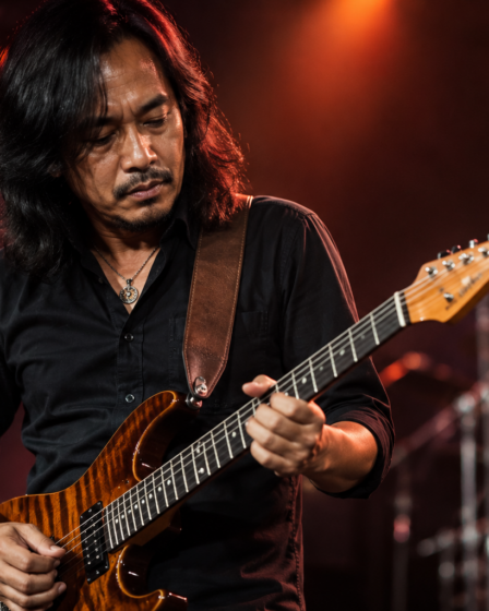 Dewa Budjana memainkan gitar elektrik saat tampil di atas panggung konser musik