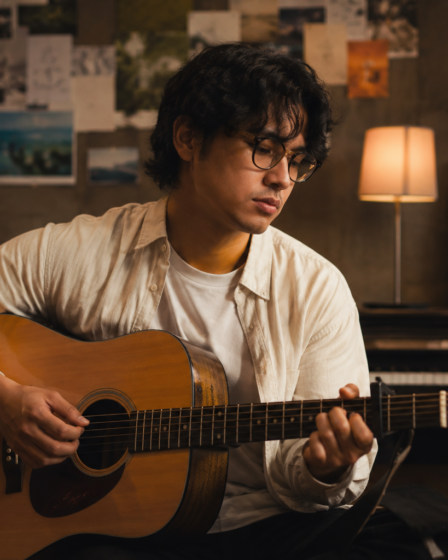 Bilal Indrajaya tampil membawakan lagu di atas panggung dengan gitar akustik dan pencahayaan konser yang hangat