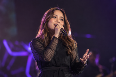 Anggi Marito saat tampil membawakan lagu di atas panggung dengan tata cahaya konser yang hangat.