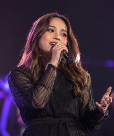 Anggi Marito saat tampil membawakan lagu di atas panggung dengan tata cahaya konser yang hangat.