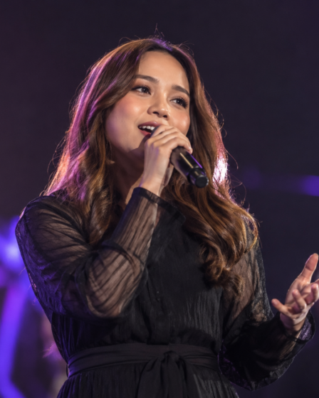 Anggi Marito saat tampil membawakan lagu di atas panggung dengan tata cahaya konser yang hangat.