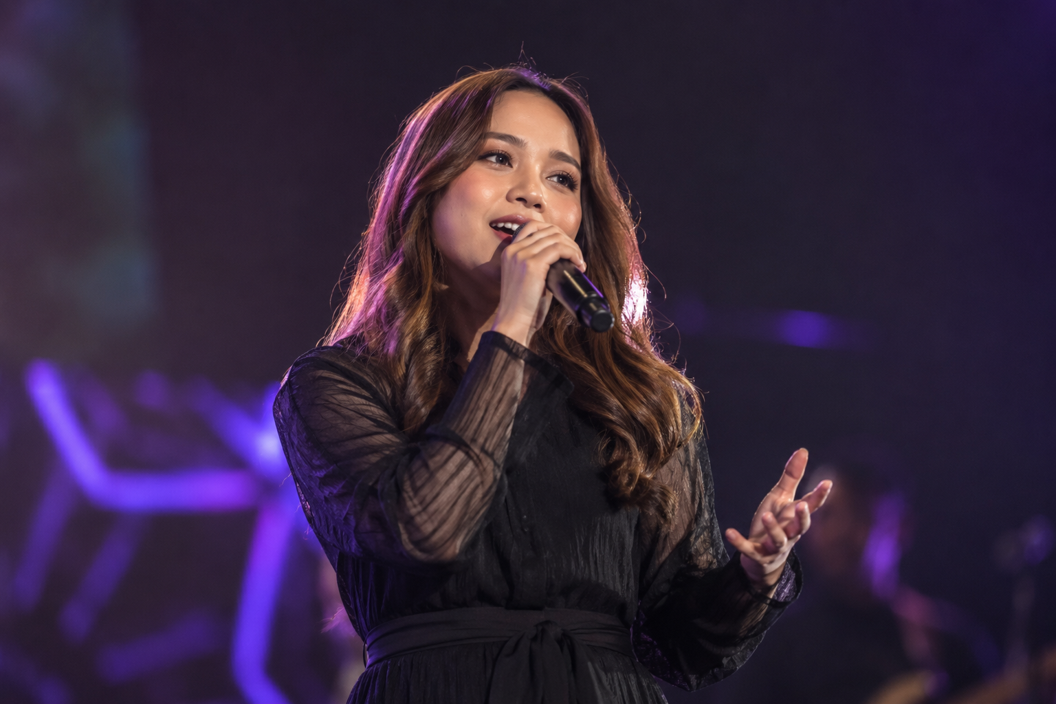 Anggi Marito saat tampil membawakan lagu di atas panggung dengan tata cahaya konser yang hangat.