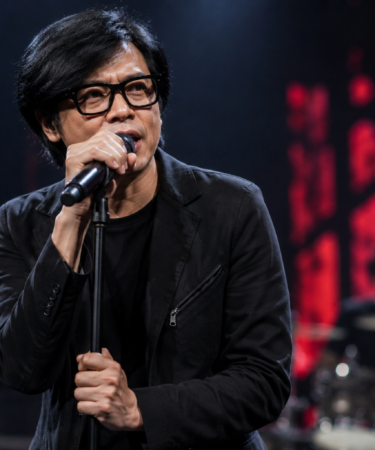 Armand Maulana tampil membawakan lagu bersama band GIGI di atas panggung konser.