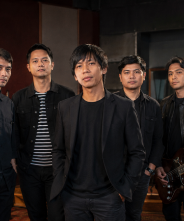 Personel D'Masiv tampil membawakan lagu di atas panggung konser dengan pencahayaan profesional dan suasana meriah