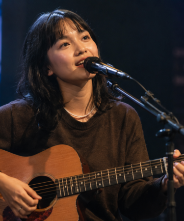 Idgitaf tampil membawakan lagu di atas panggung dengan pencahayaan hangat dan suasana intim