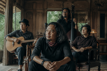 Payung Teduh tampil di atas panggung membawakan lagu folk dengan suasana konser yang hangat dan pencahayaan artistik.