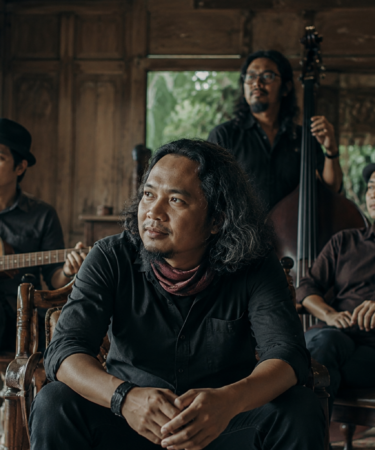 Payung Teduh tampil di atas panggung membawakan lagu folk dengan suasana konser yang hangat dan pencahayaan artistik.
