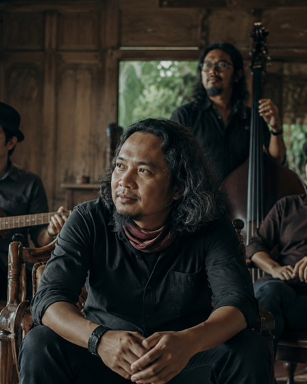 Payung Teduh tampil di atas panggung membawakan lagu folk dengan suasana konser yang hangat dan pencahayaan artistik.
