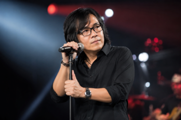 Ari Lasso tampil bernyanyi di atas panggung dengan pencahayaan konser yang dramatis