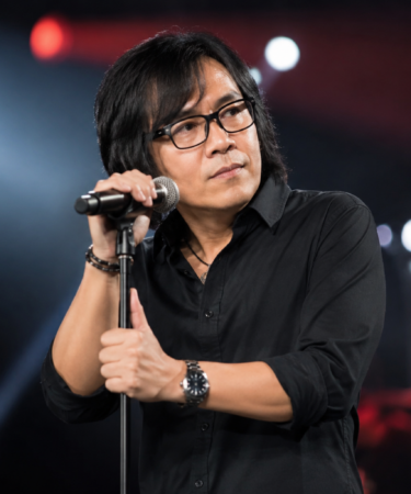 Ari Lasso tampil bernyanyi di atas panggung dengan pencahayaan konser yang dramatis