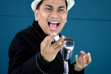 Tompi tampil di atas panggung membawakan lagu jazz dengan iringan band dan pencahayaan konser profesional.