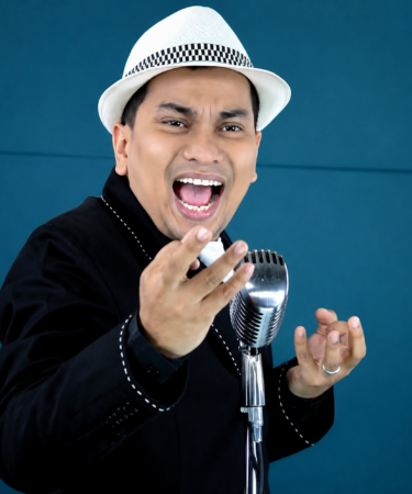 Tompi tampil di atas panggung membawakan lagu jazz dengan iringan band dan pencahayaan konser profesional.