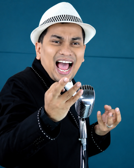 Tompi tampil di atas panggung membawakan lagu jazz dengan iringan band dan pencahayaan konser profesional.