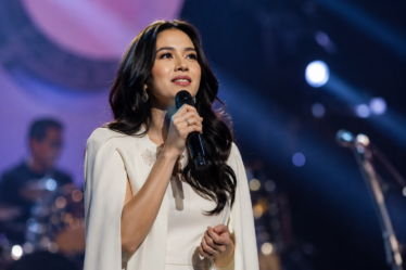 Raisa tampil membawakan lagu dalam sebuah konser musik dengan tata panggung megah dan pencahayaan profesional.