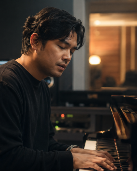Musisi Petra Sihombing tampil di atas panggung sambil memainkan gitar dengan pencahayaan konser yang hangat.