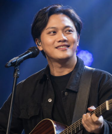Rizky Febian tampil membawakan lagu di atas panggung konser dengan pencahayaan profesional dan penampilan yang khas.