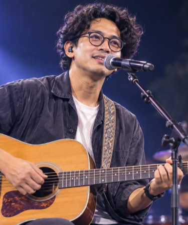 Budi Doremi tampil membawakan lagu di atas panggung konser dengan pencahayaan profesional dan penonton yang antusias